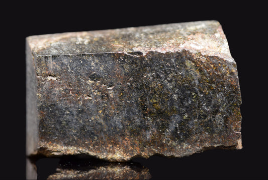 NWA 11757 Ureilite meteorite specimen showing dark fusion crust and crystalline interior, weighing 7.6 grams.