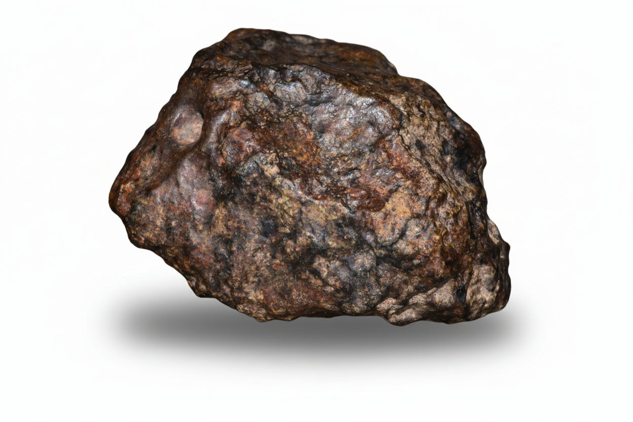 Natural fragment of NWA 13272 ungrouped achondrite meteorite showing dark, textured surface, weighs 10.7 grams.