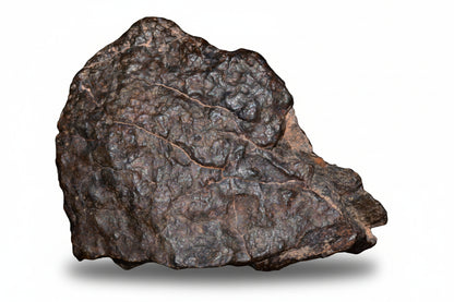 Natural fragment of NWA 13272 ungrouped achondrite meteorite showing rough, irregular surface with dark coloration and mineral textures.