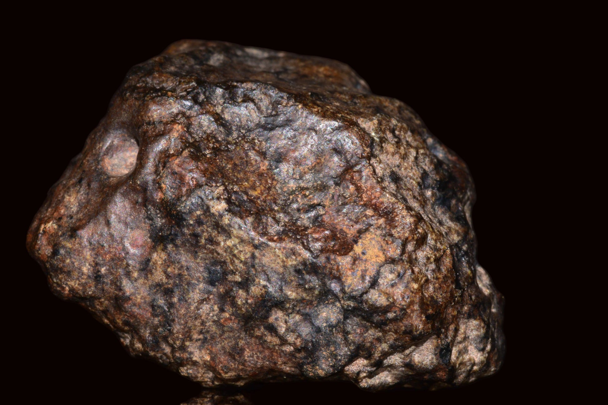 Complete natural fragment of NWA 13272 ungrouped achondrite meteorite from Mauritania, showing rough surface and mineral details.