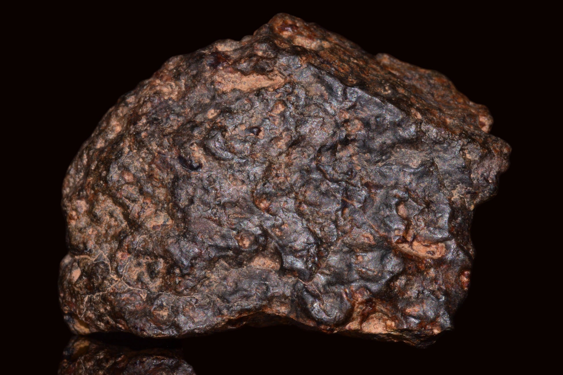 Natural fragment of NWA 13272 ungrouped achondrite meteorite, 11.5g, with rough, dark surface and metallic mineral patches.